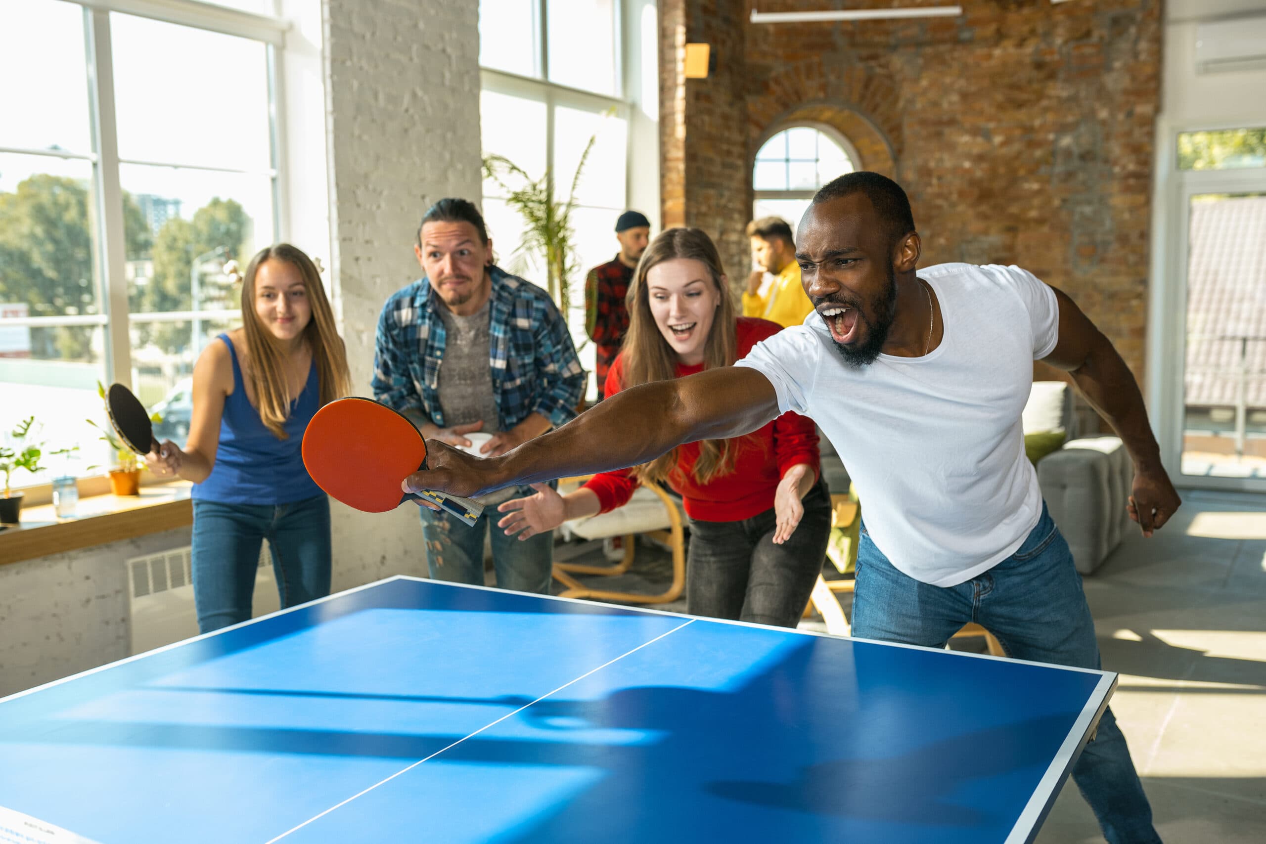 Friends playing table tennis at a social night